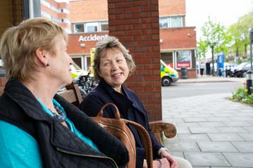Two women talking to each other outside a hospital